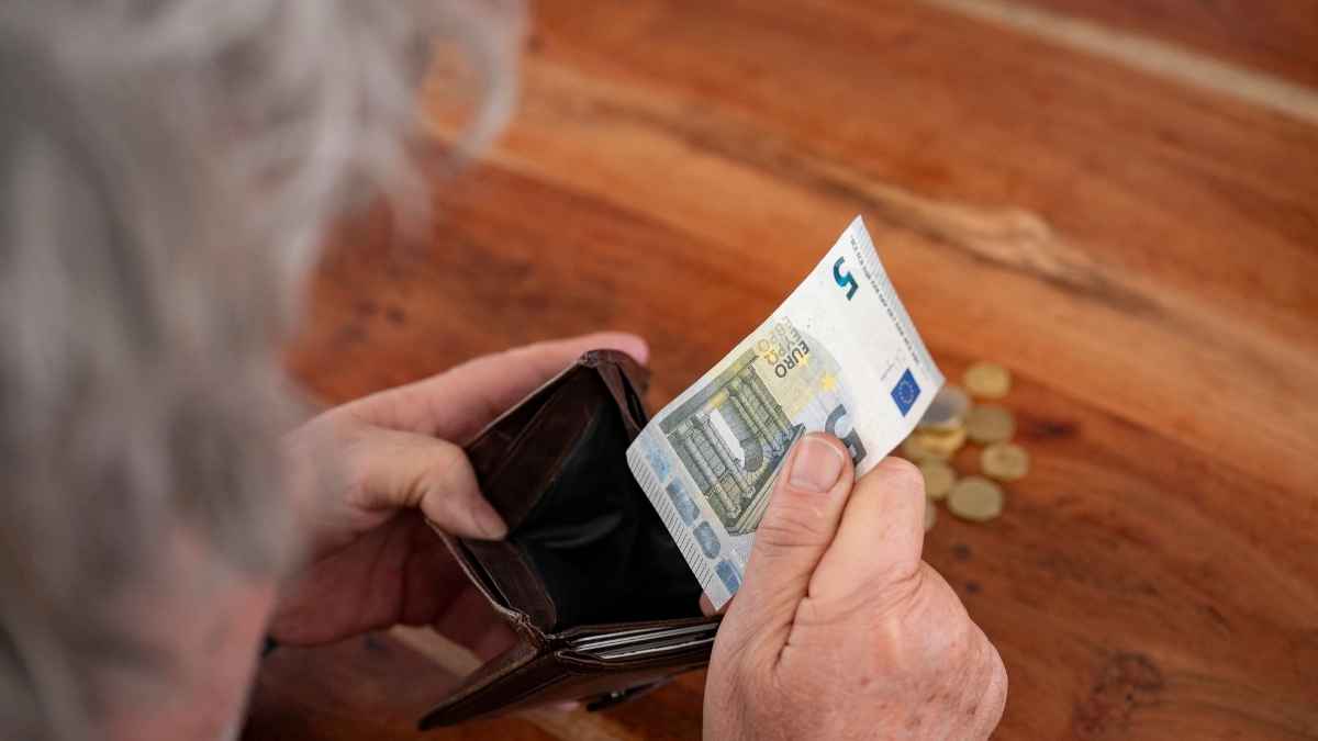 Persona mayor revisando cartera vacía tras nuevo cambio en la Seguridad Social que reduce la pensión en agosto