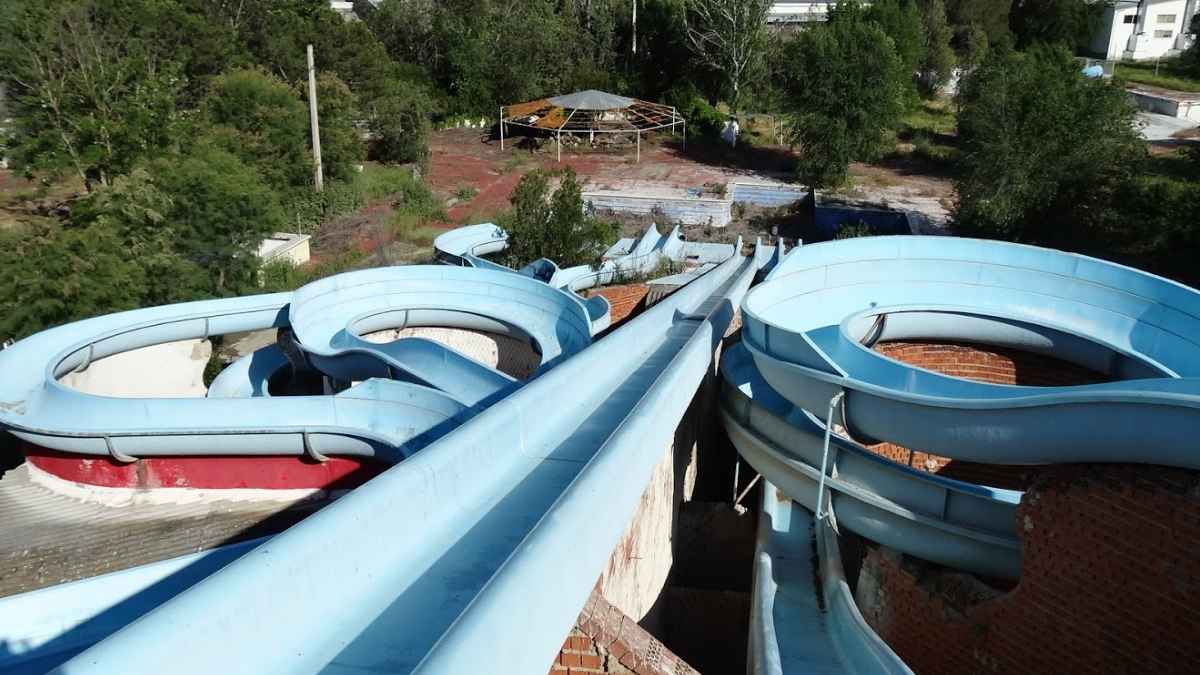 Parque acuático abandonado en España con toboganes deteriorados y vegetación silvestre