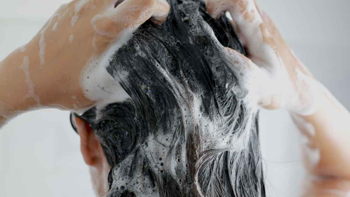 Persona lavándose el cabello con champú para evitar riesgos que alerta una peluquera