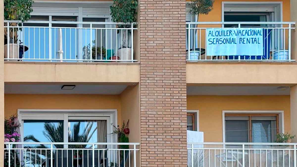 Cartel anunciando alquiler vacacional en un balcón de apartamento turístico