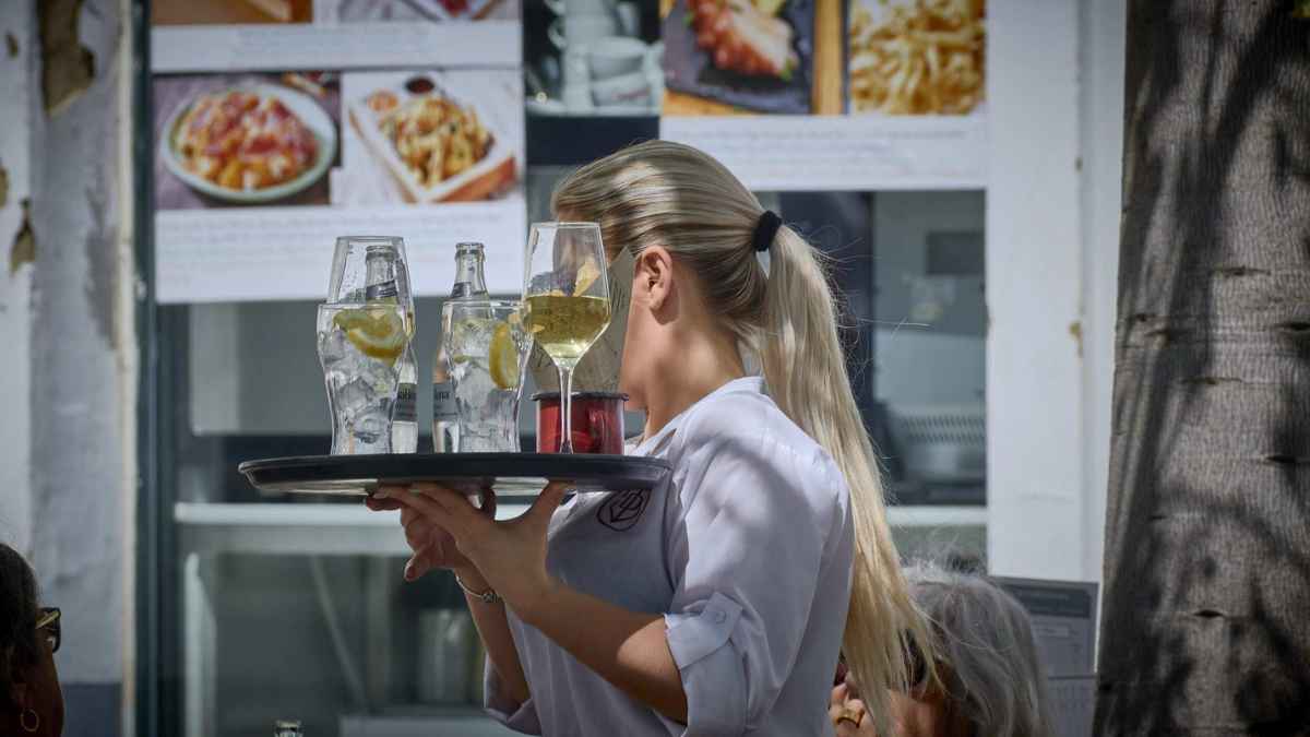 Camarera trabajando en terraza durante el récord de afiliados a la Seguridad Social en junio
