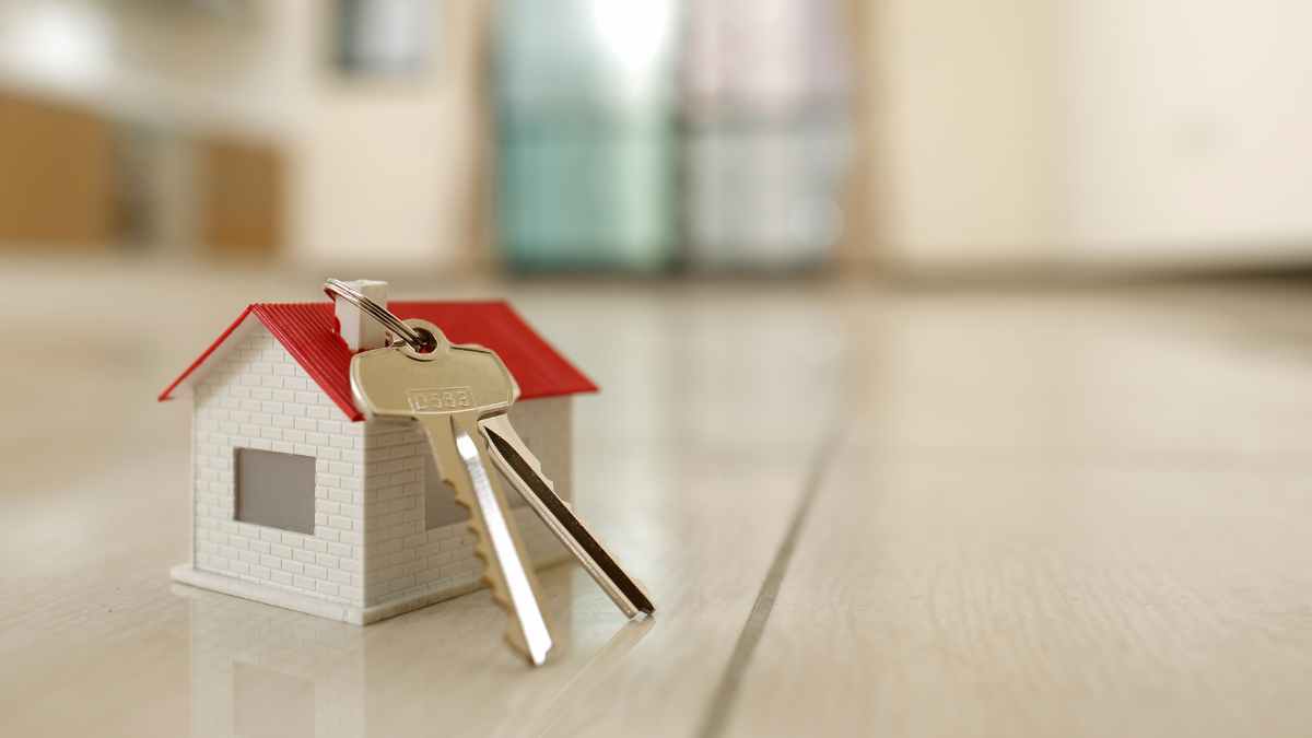 Llaves de casa sobre el suelo junto a una maqueta, simbolizando adquisición de vivienda por usucapión en Argentina.