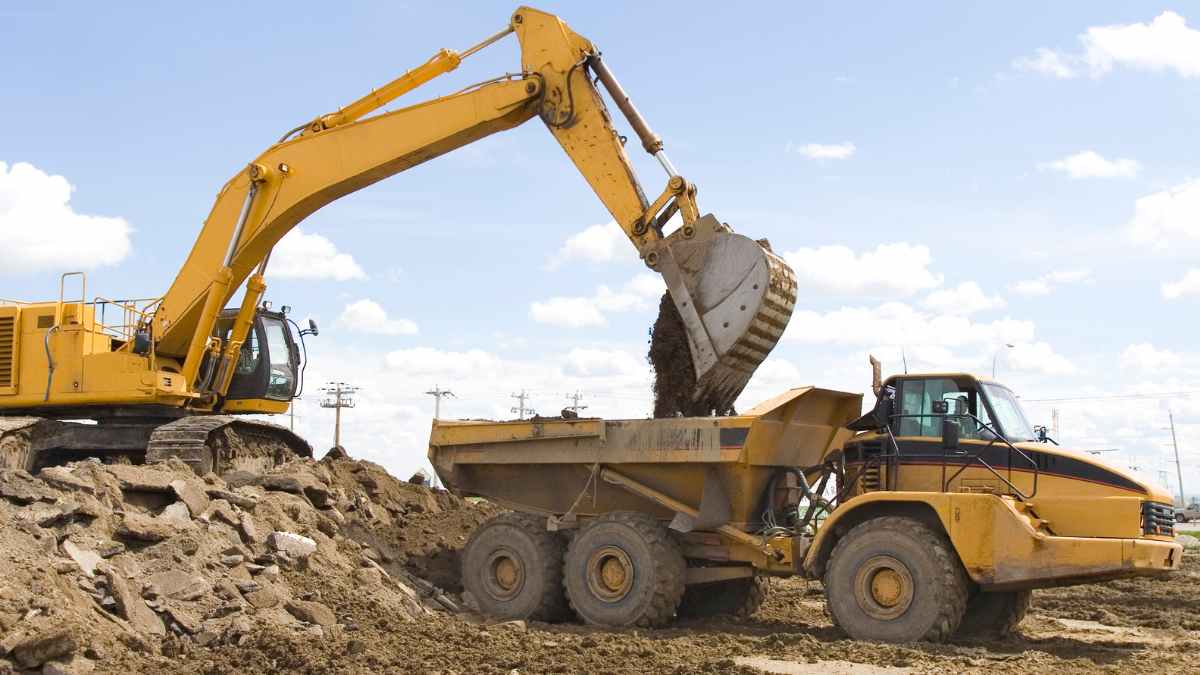 Excavadora cargando tierra en un camión volquete durante una obra de construcción en España