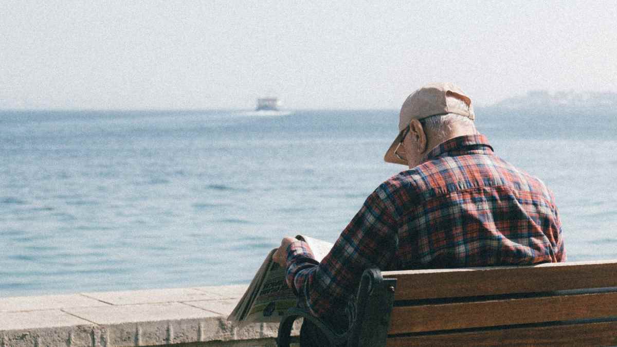 Jubilado leyendo el periódico junto al mar, devolución del IRPF a mutualistas en pago único 2025