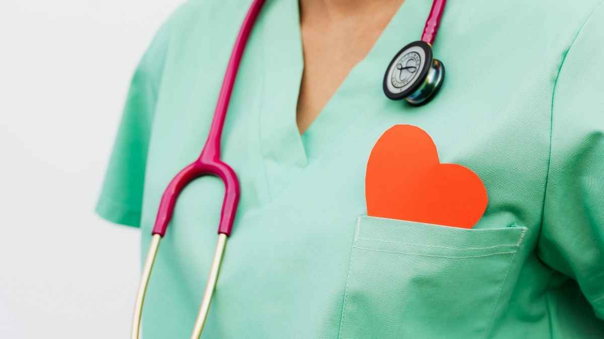 Enfermera con uniforme verde, fonendoscopio rosa y corazón naranja en el bolsillo