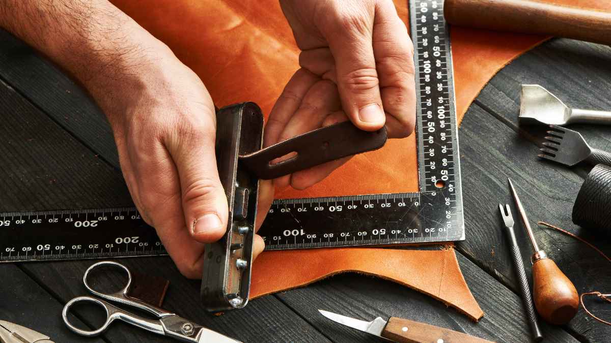 Artesano cortando cinturón de cuero en taller rural, posible prohibición de la UE sobre la piel animal