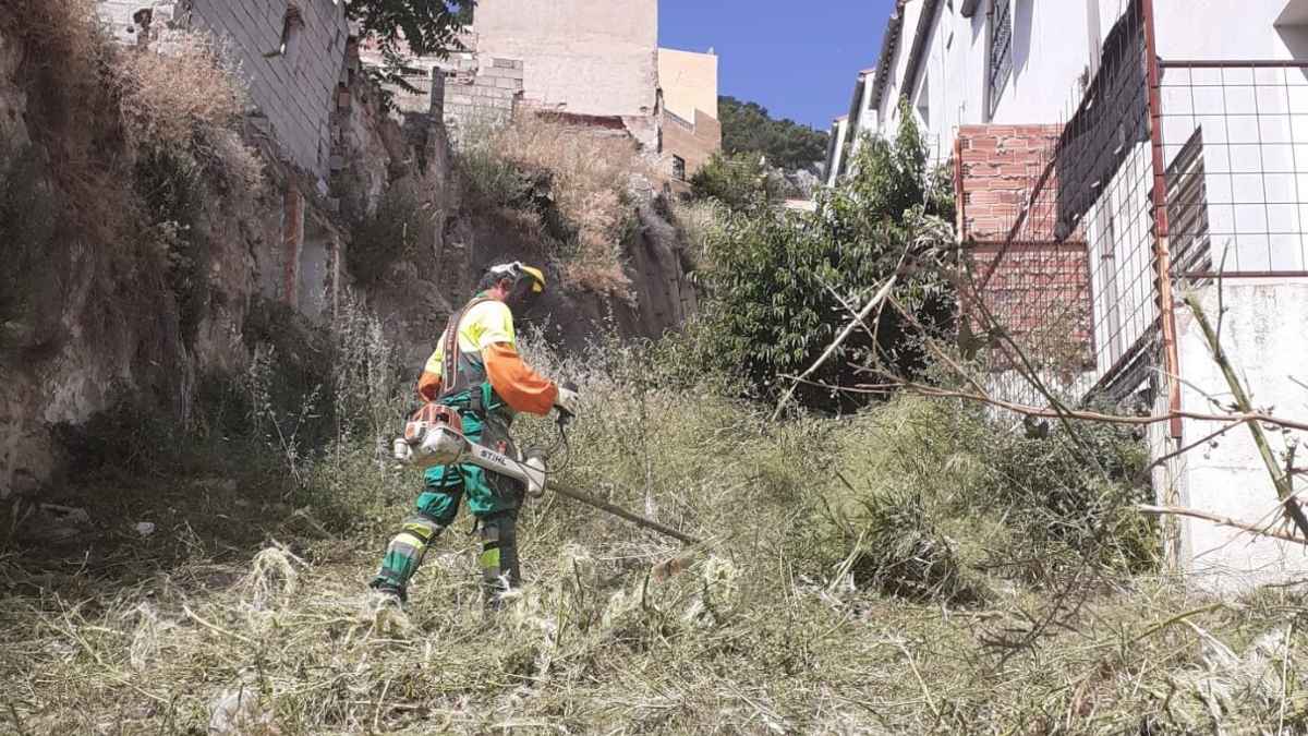Operario con desbrozadora limpiando una parcela urbana por la normativa antiincendios que afecta a una jubilada pensionista