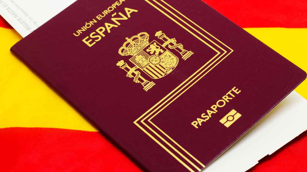 Pasaporte español sobre la bandera, símbolo de la nacionalidad concedida tras sentencia de la Audiencia Nacional