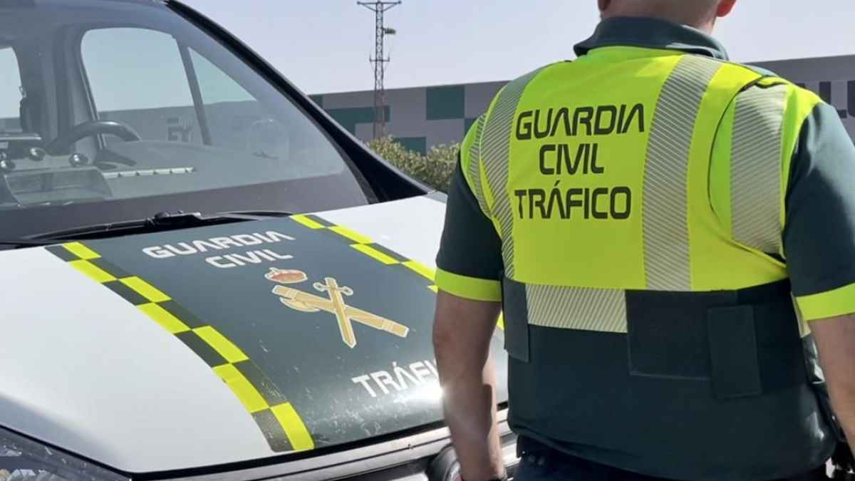 Agente de la Guardia Civil de Tráfico junto a coche patrulla en controles de rotondas por multas DGT