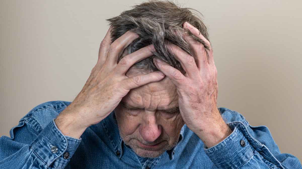 Hombre mayor preocupado con las manos en la cabeza por una pensión de 800 euros tras 45 años cotizados