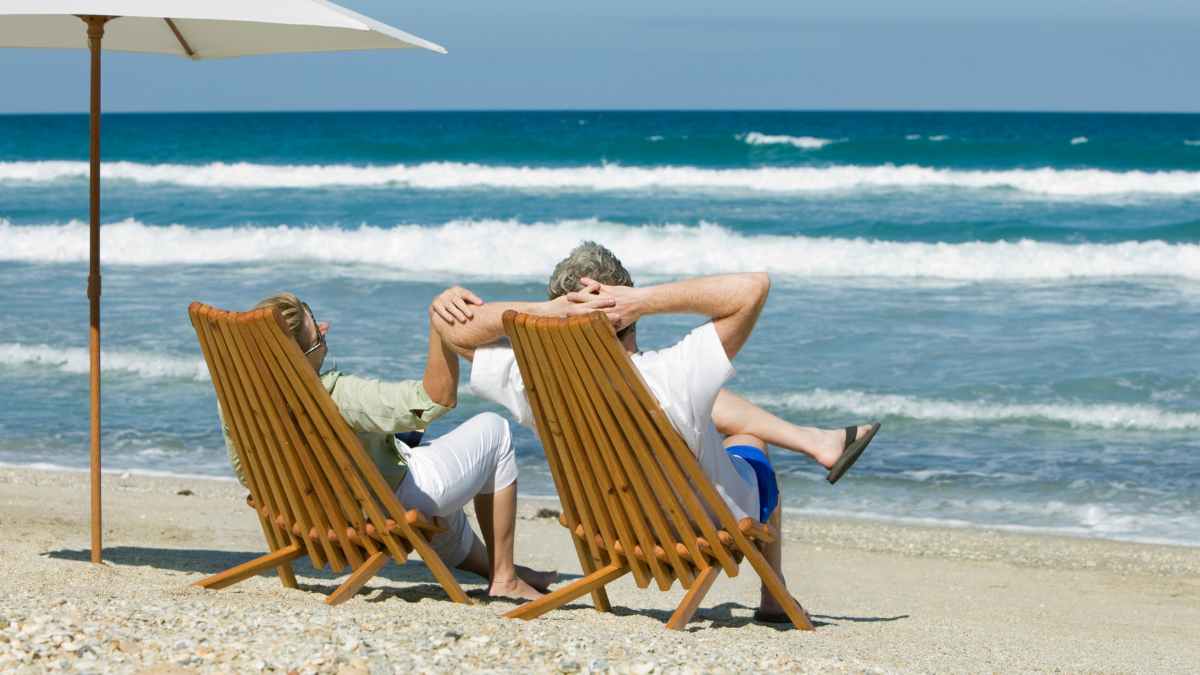 Pareja jubilada relajándose en la playa; guía de pensión de jubilación 2025-2027 según años cotizados y sueldo.