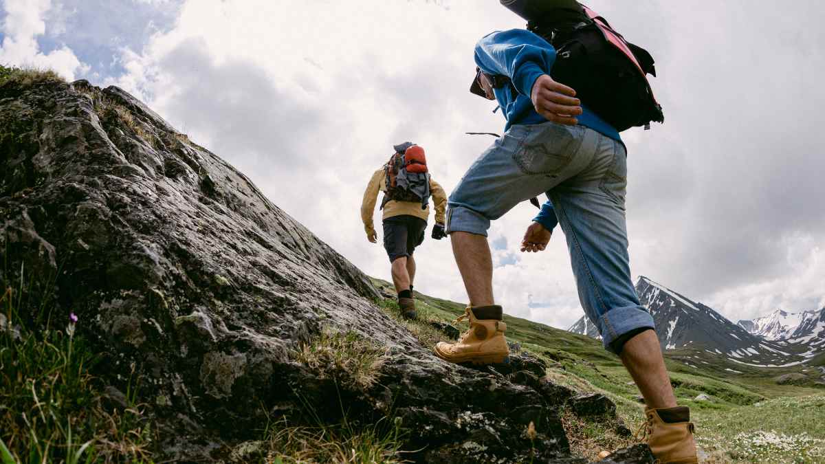 Dos excursionistas suben una ladera rocosa en la montaña, imagen del hallazgo de casi 600 monedas de oro