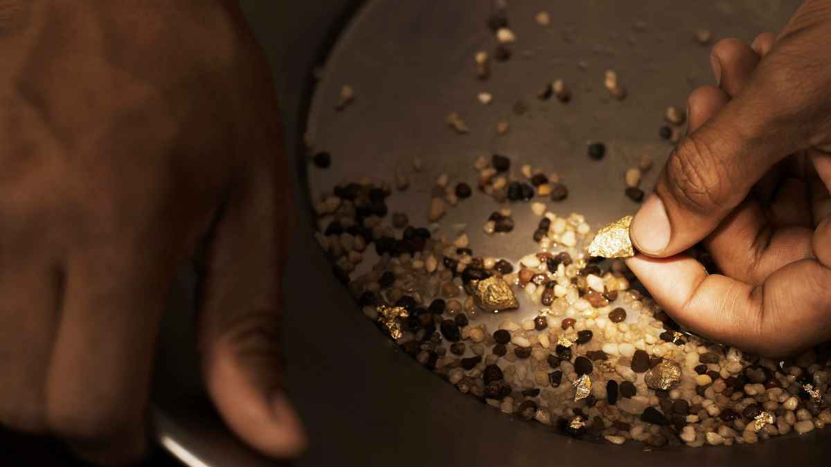 Persona sujetando una pepita de oro obtenida de un recipiente, representando el descubrimiento submarino de la NASA que podría beneficiar la economía española