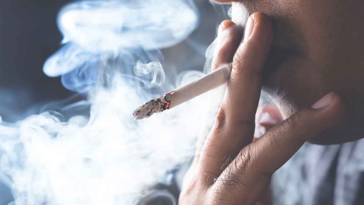 Persona fumando un cigarrillo con humo visible en primer plano