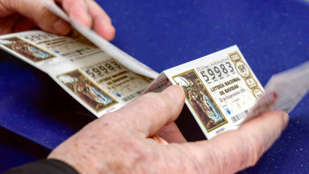 Manos sosteniendo décimos de la Lotería de Navidad 2024 en España