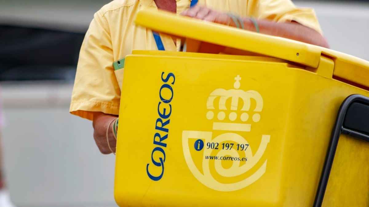 Cartero de Correos con carrito amarillo durante el reparto de cartas