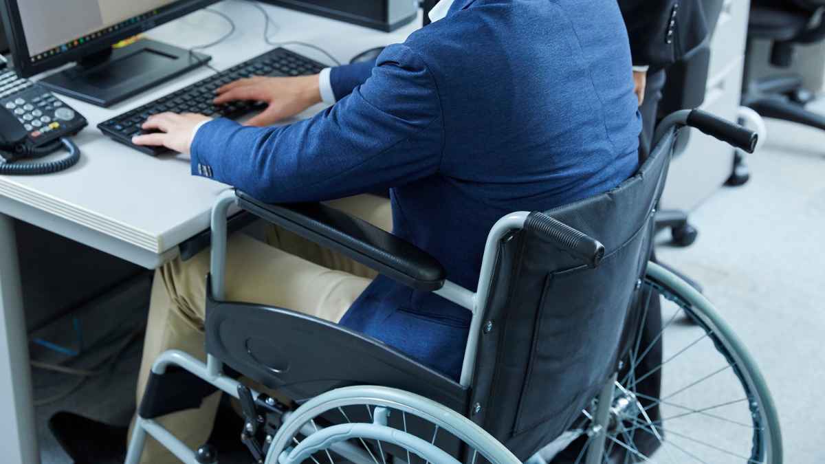 Trabajador en silla de ruedas en oficina tras cambios de la Ley 2/2025 sobre incapacidad permanente