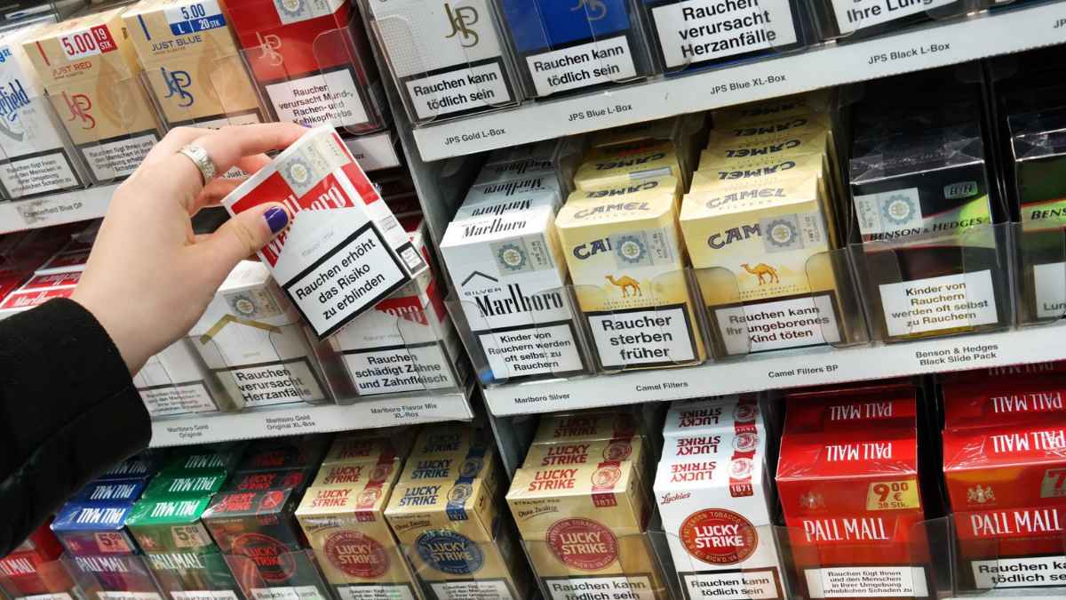 Estantería de estanco con cajetillas de tabaco Marlboro, Camel, Chesterfield y otras marcas con advertencias sanitarias
