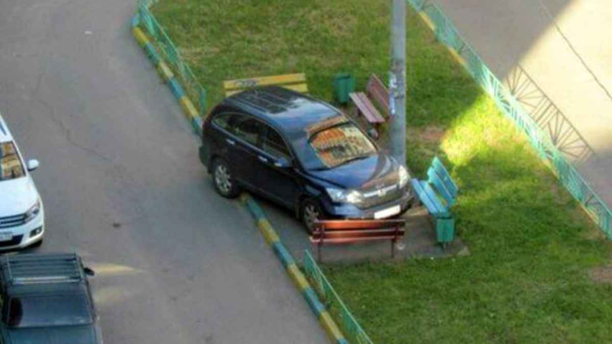 Coche mal aparcado sobre acera y bancos en zona residencial