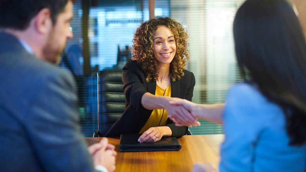 Mujer trabajadora joven en reunión laboral estrechando la mano