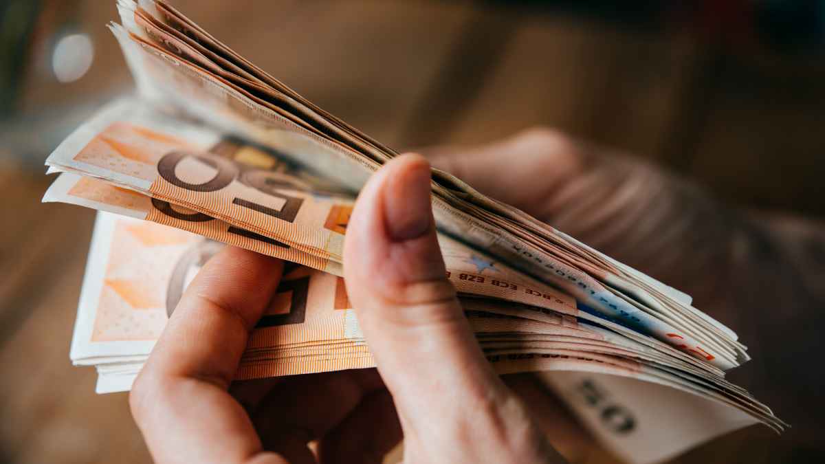 Manos contando billetes de cincuenta euros relacionados con ayudas del SEPE