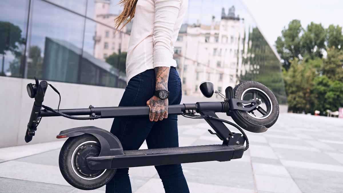 Persona transportando un patinete eléctrico por la ciudad tras la creación del registro obligatorio de la DGT en España