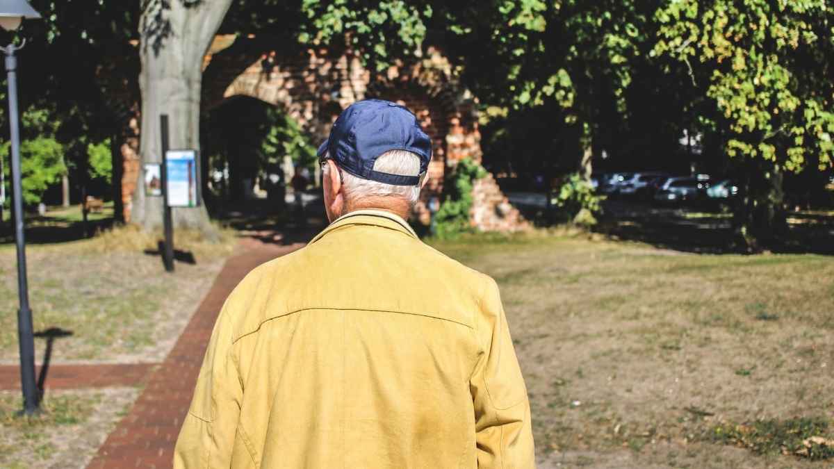 Hombre mayor jubilado con gorra caminando por un parque en España
