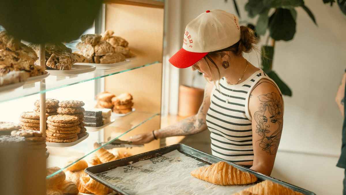 Trabajadora en una pastelería de Barcelona manipulando bandejas de bollería tras sentencia por horas extra no pagadas