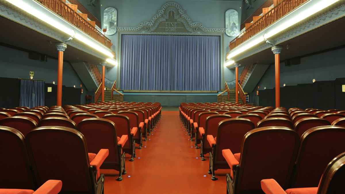 Interior del Cine Doré en Madrid con butacas rojas y escenario, donde se ofrecen tres meses de cine gratuito.