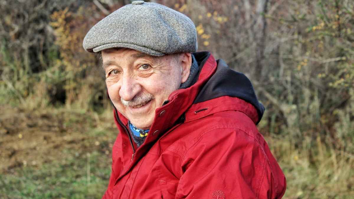 Médico jubilado sonriente con chaqueta roja que ofrece consejos a los jóvenes sobre cómo asegurar una pensión tranquila