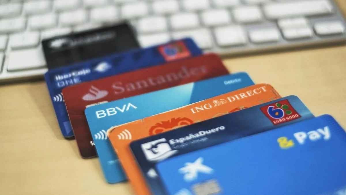 Tarjetas bancarias de distintos bancos sobre un escritorio junto a un teclado