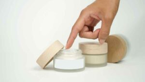 Persona aplicando crema de un frasco cosmético retirado del mercado por contener sustancias que pueden irritar la piel