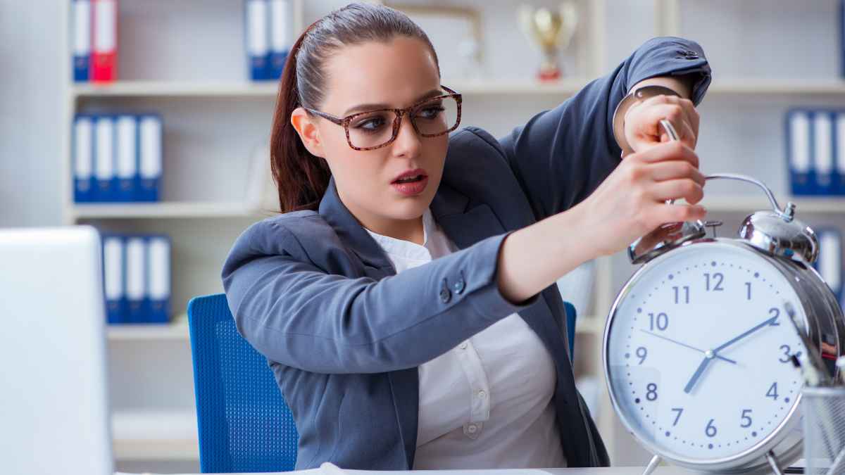 Mujer preocupada mirando un reloj grande simbolizando impuntualidad y despido improcedente con indemnización laboral.