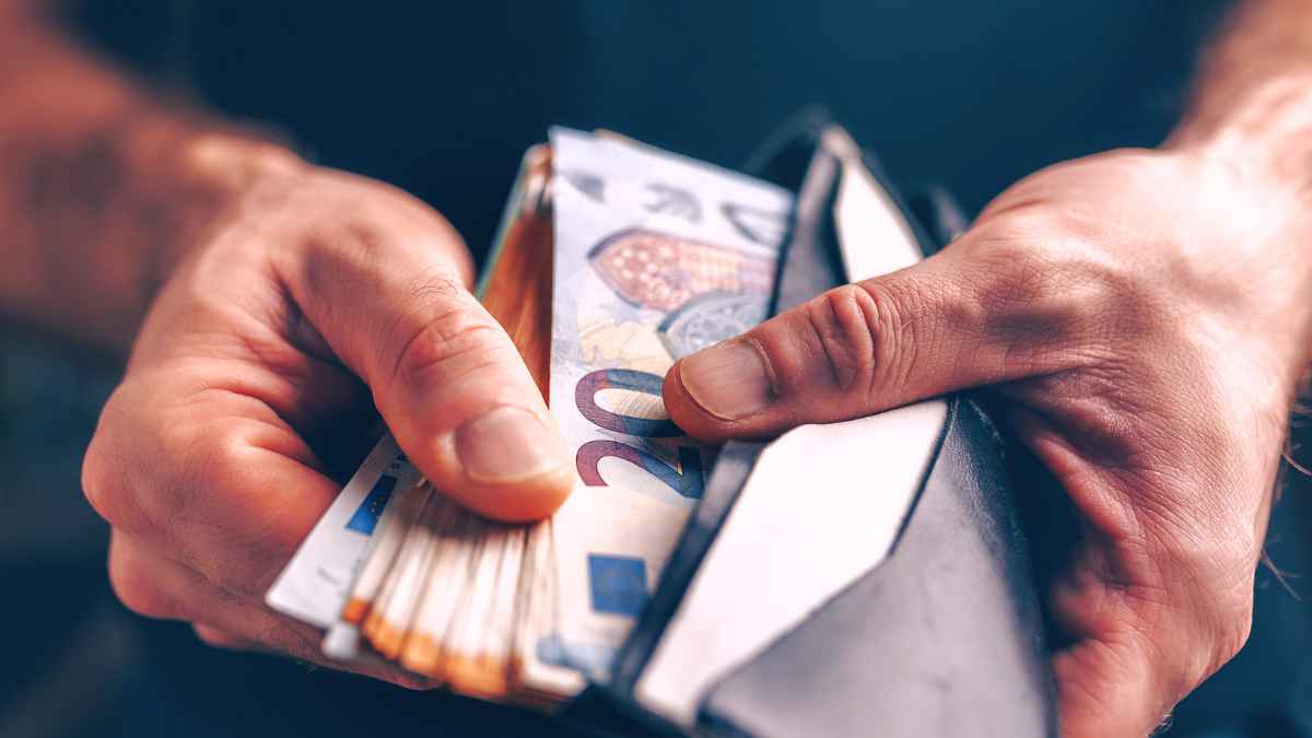 Manos sacando billetes de euro de una cartera para ilustrar la ayuda de 400 euros del Gobierno en octubre de 2025