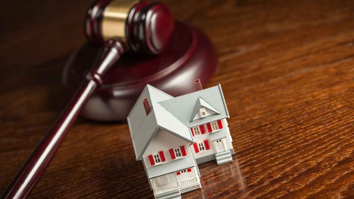 Casa embargada junto a un mazo judicial representando una subasta de viviendas en España.