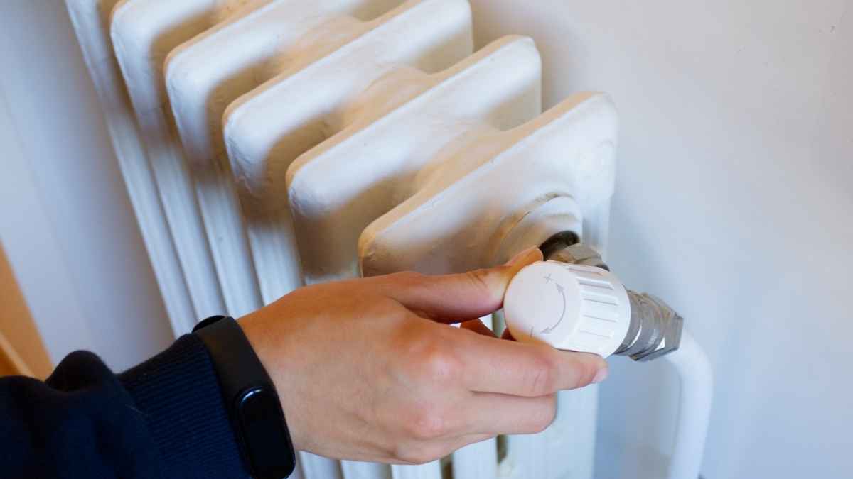 mano ajustando el radiador de la calefacción de gas en un hogar en invierno