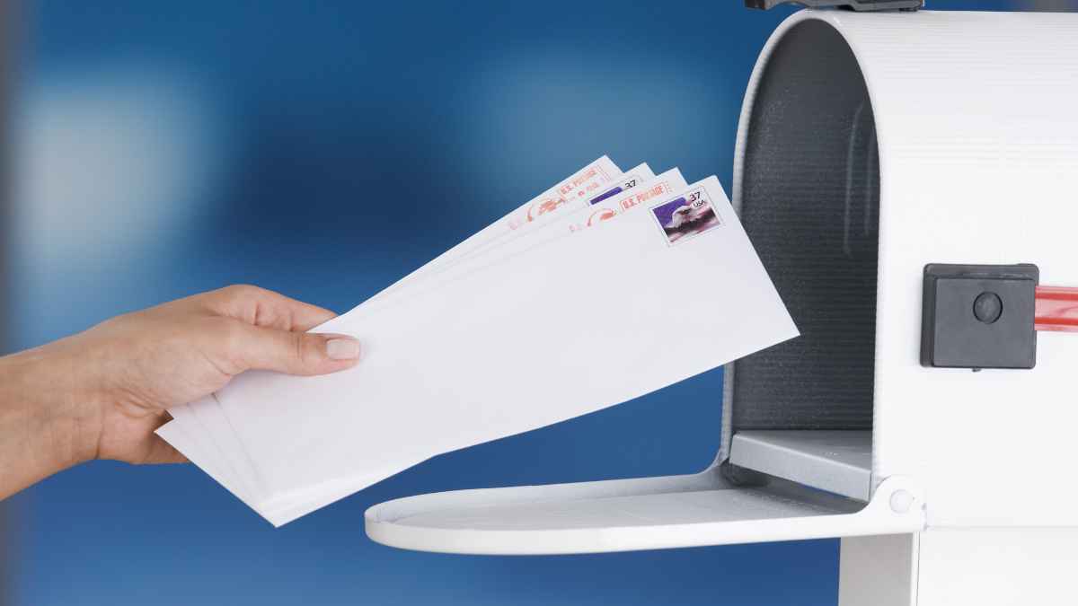 Mano de un cartero colocando cartas en un buzón representando el despido de un trabajador por enfermedad en La Poste.