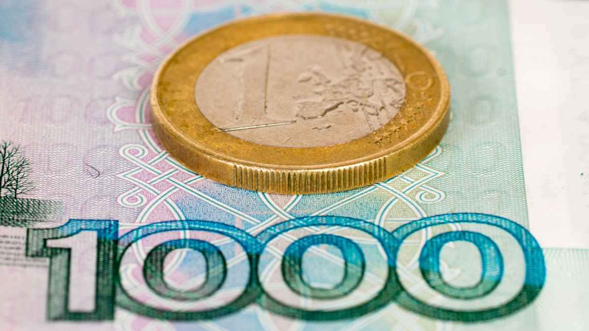 Moneda de un euro sobre billete con el número 1000 que representa el cheque de 1.000 euros por hijo de la Seguridad Social