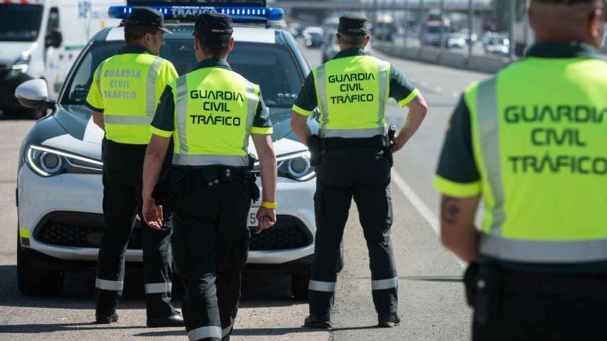 Agentes de la Guardia Civil de Tráfico realizando un control en carretera junto a un vehículo oficial.
