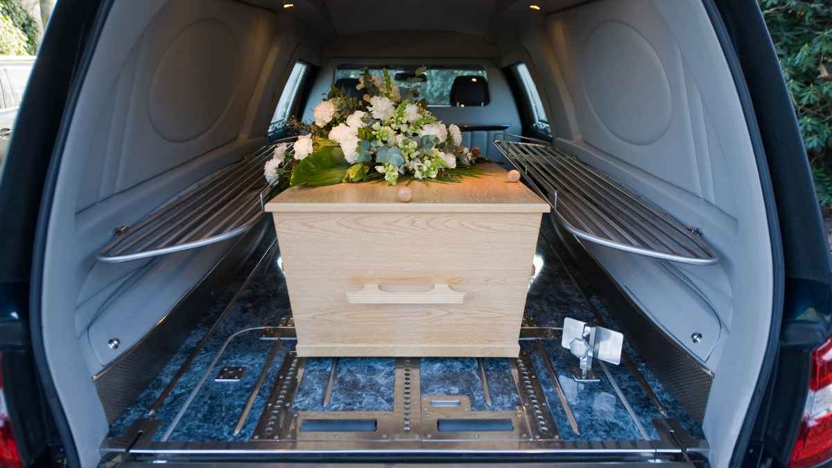 Ataúd con flores en el interior de un coche fúnebre de una funeraria