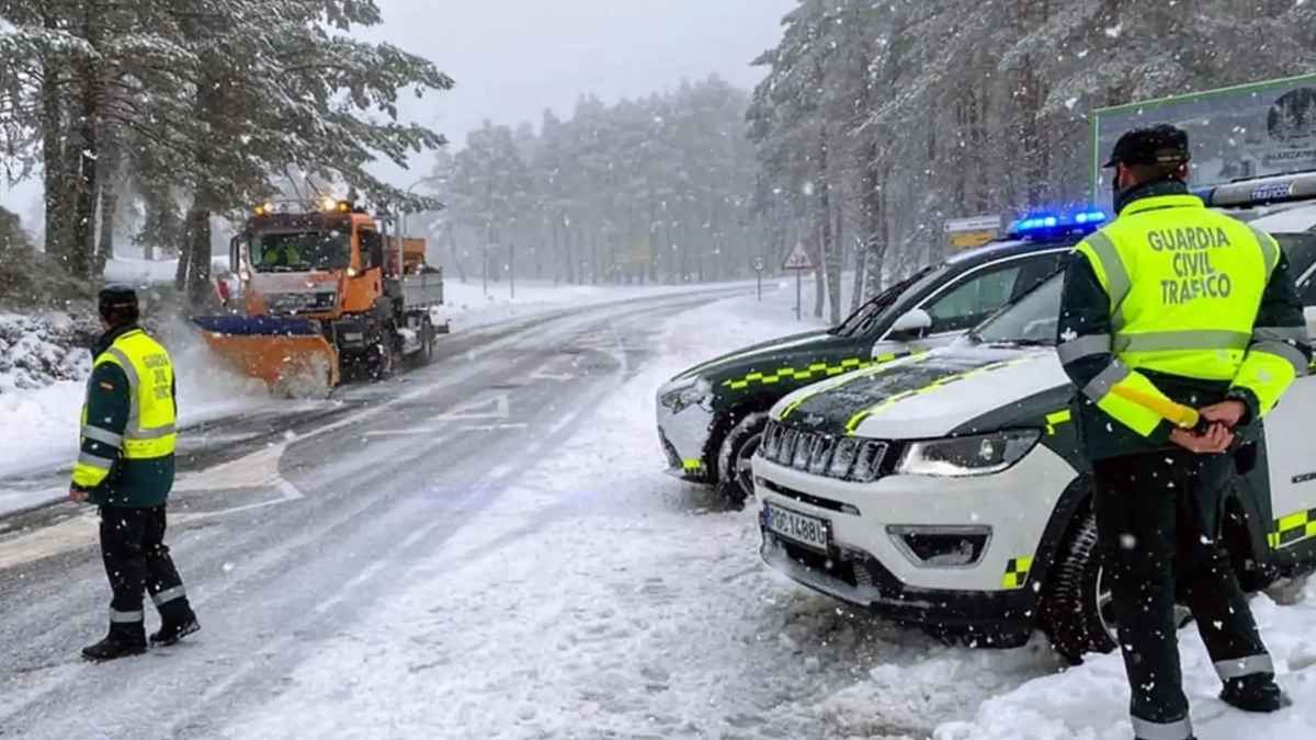 Control de la Guardia Civil de Tráfico en una carretera nevada mientras un quitanieves limpia la vía