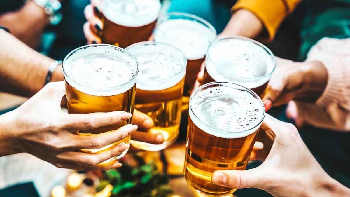 Varias personas brindando con vasos de cerveza durante una reunión social de empresa.