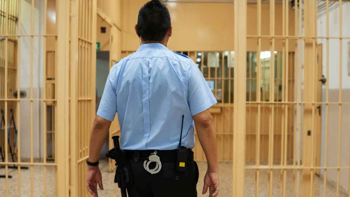 Funcionario de prisiones en un pasillo de celdas durante su jornada laboral, imagen representativa de las oposiciones a Ayudantes de Instituciones Penitenciarias OEP 2025.