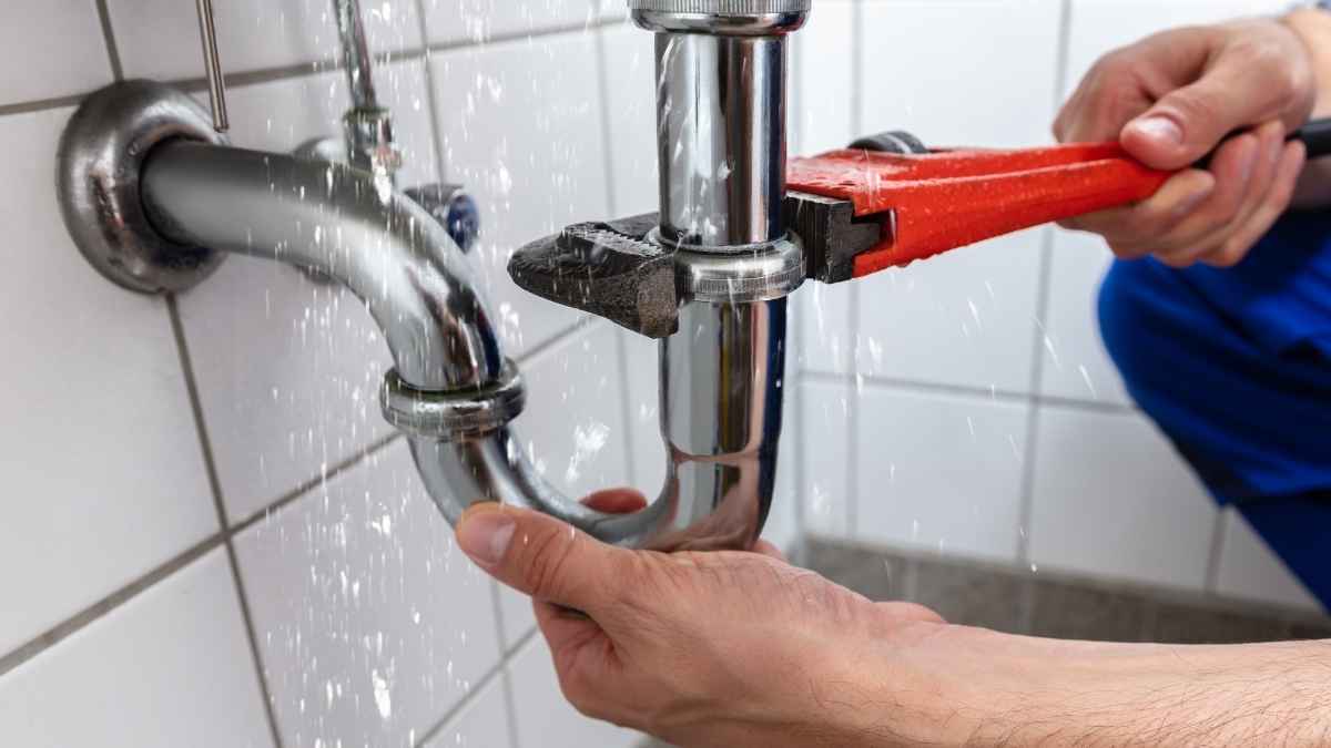 Fontanero reparando una tubería con fuga utilizando una llave inglesa