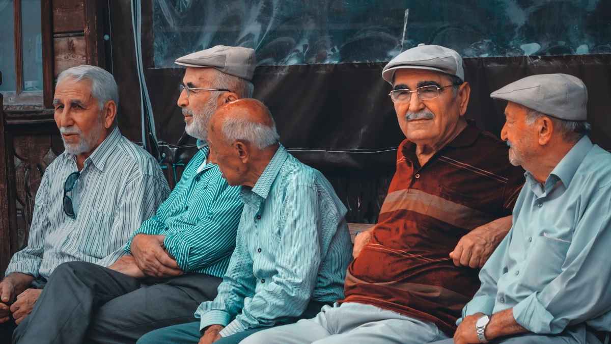 Grupo de personas mayores sentadas al aire libre, representando a pensionistas afectados por la subida de las pensiones mínimas.