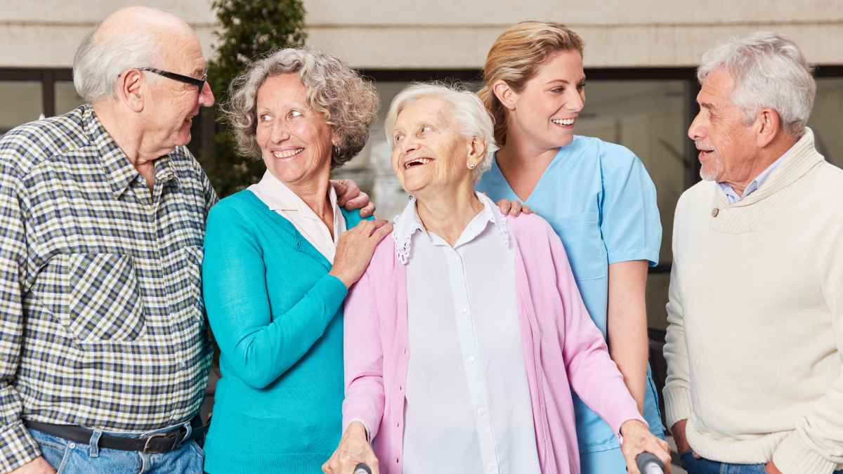Personas mayores sonrientes conversan junto a una cuidadora en un entorno tranquilo