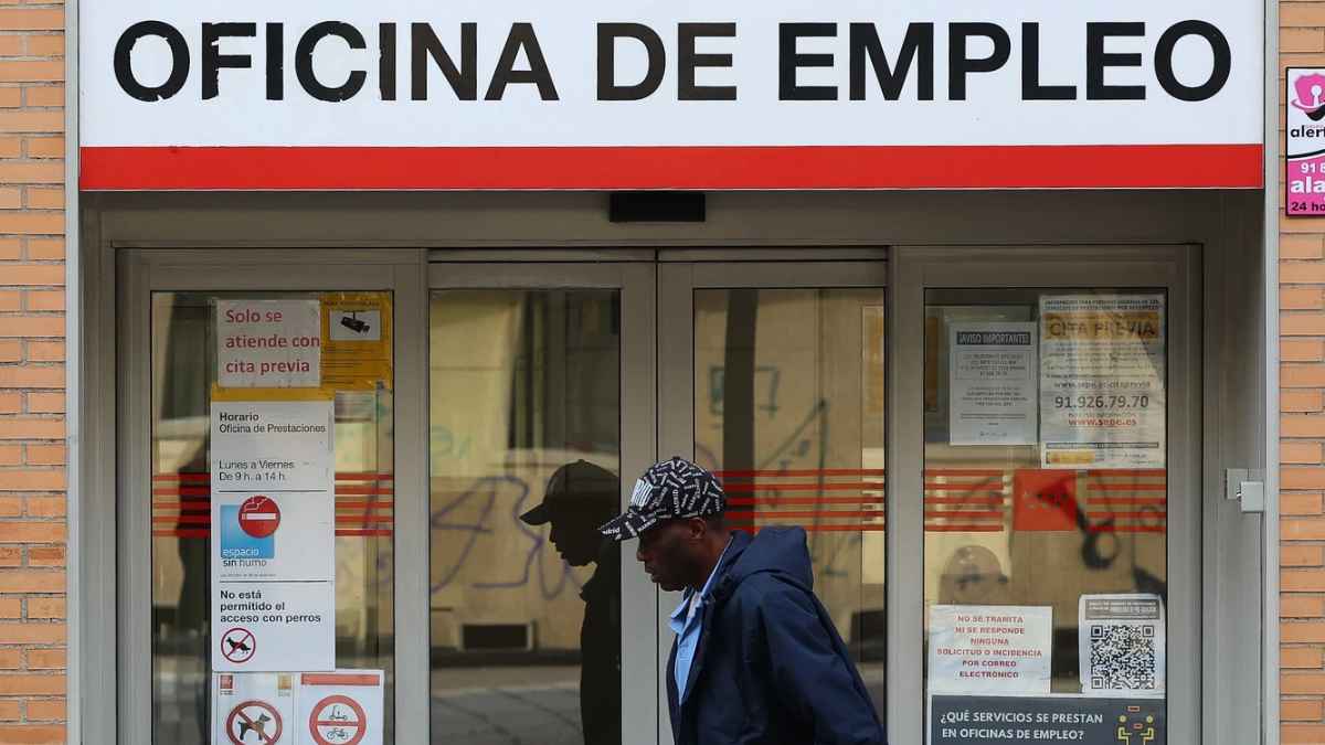 Persona caminando frente a una oficina de empleo donde se gestionan solicitudes de paro y trámites del SEPE