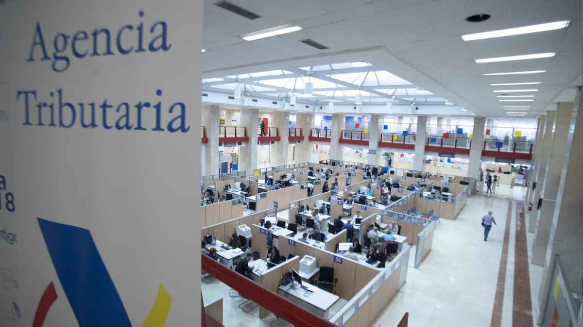 Oficina de la Agencia Tributaria con trabajadores atendiendo gestiones relacionadas con deudas y Hacienda