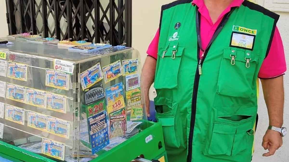 Puesto de venta de cupones de la ONCE atendido por un vendedor con el uniforme oficial.