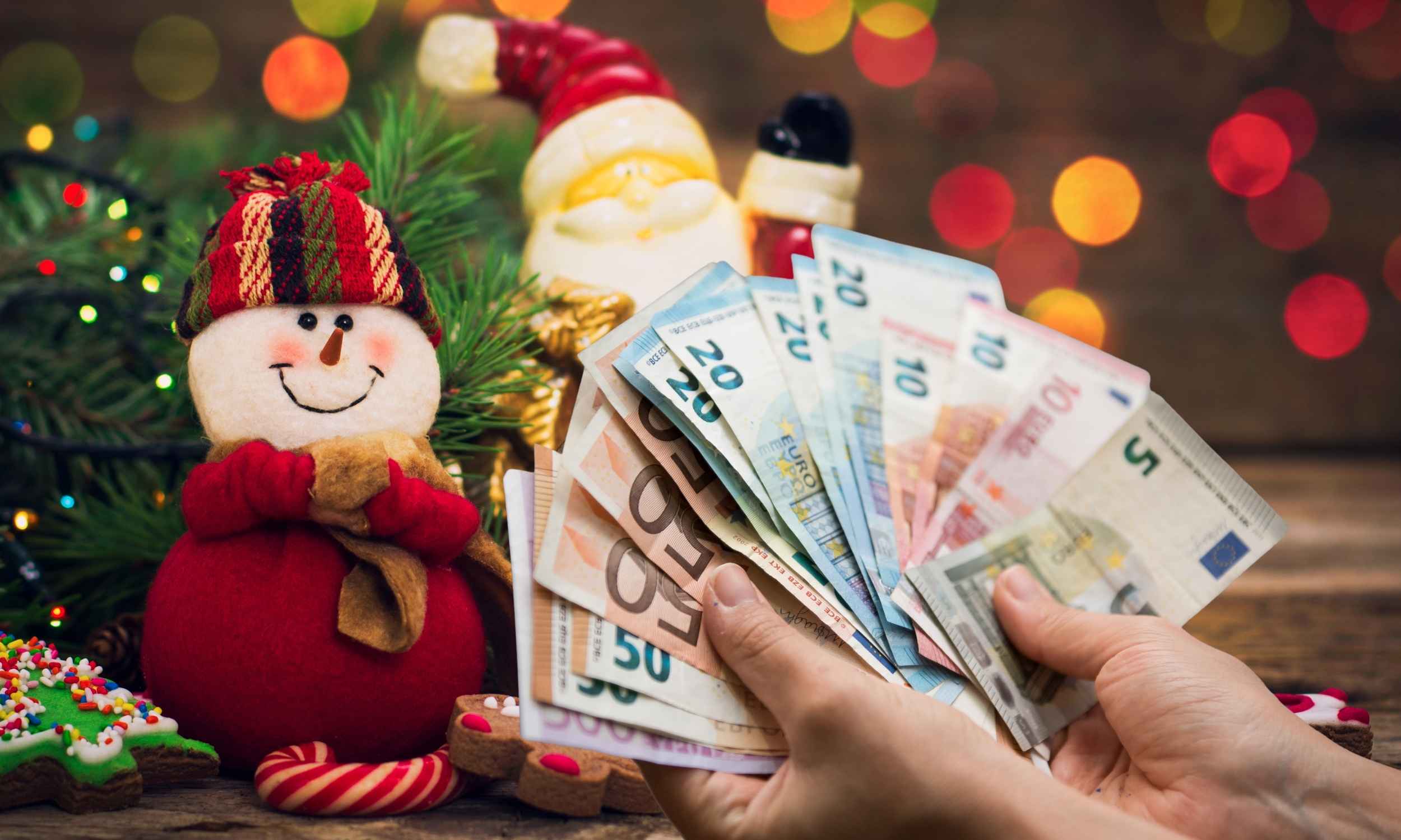 Manos contando billetes de euro junto a adornos navideños que representan la paga extra de Navidad para pensionistas 2025